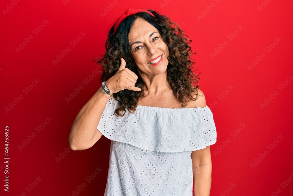 Middle age hispanic woman wearing casual clothes smiling doing phone gesture with hand and fingers like talking on the telephone. communicating concepts. Middle age hispanic woman wearing casual clothes smiling doing phone gesture with hand and fingers like talking on the telephone. communicating concepts.