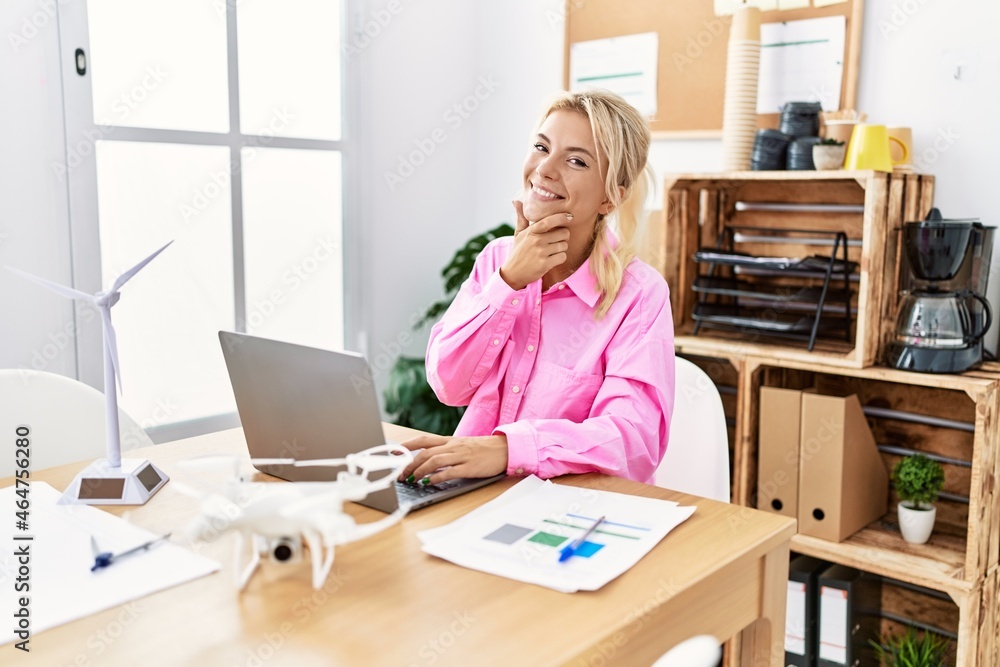 Young caucasian woman working at the office looking confident at the camera smiling with crossed arms and hand raised on chin. thinking positive. Young caucasian woman working at the office looking confident at the camera smiling with crossed arms and hand raised on chin. thinking positive.