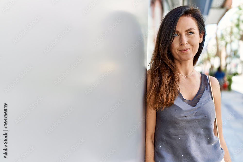 Beautiful caucasian woman looking elegant and happy leaning on a wall outdoors on a sunny day Beautiful caucasian woman looking elegant and happy leaning on a wall outdoors on a sunny day