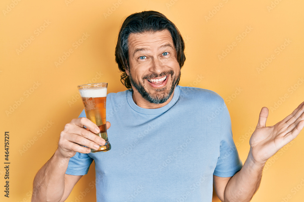 Middle age caucasian man drinking a pint of beer celebrating achievement with happy smile and winner expression with raised hand Middle age caucasian man drinking a pint of beer celebrating achievement with happy smile and winner expression with raised hand