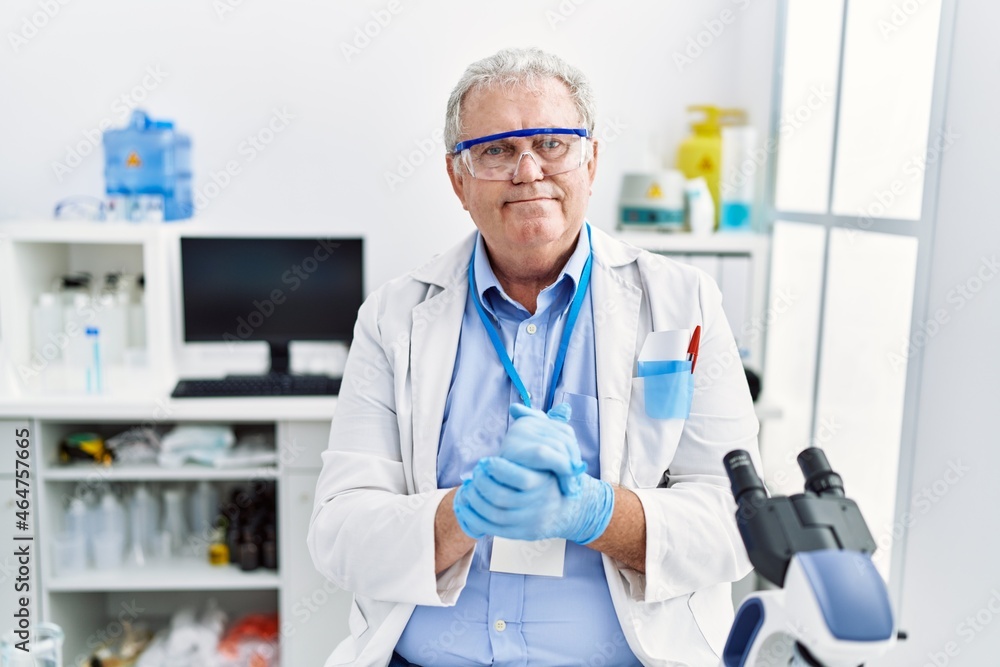 Middle age grey-haired man smiling confident wearing scientist uniform at laboratory