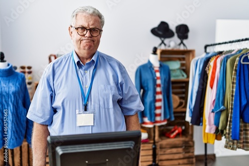 Senior man with grey hair working as manager at retail boutique skeptic and nervous, frowning upset because of problem. negative person.