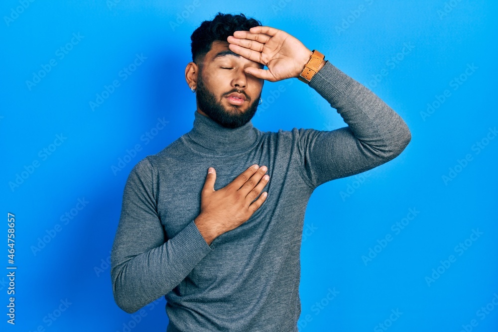 Arab man with beard wearing turtleneck sweater touching forehead for illness and fever, flu and cold, virus sick Arab man with beard wearing turtleneck sweater touching forehead for illness and fever, flu and cold, virus sick