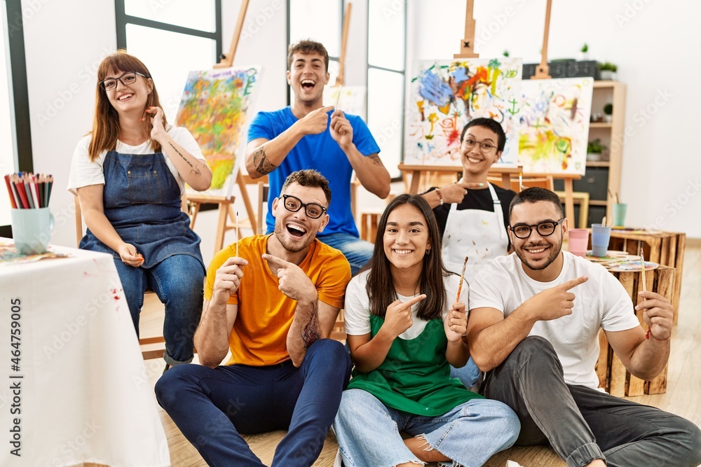 Group of people sitting at art studio smiling happy pointing with hand and finger