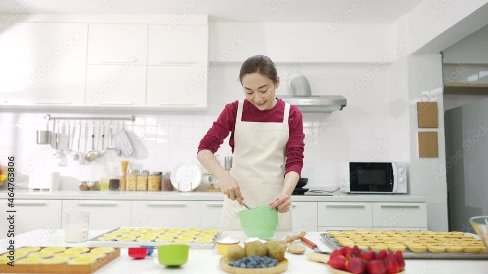 Asian woman bakery shop owner preparing bakery in the kitchen. Adult female making whipping cream from fresh milk on the table. Small business entrepreneur and indoor activity lifestyle baking concept