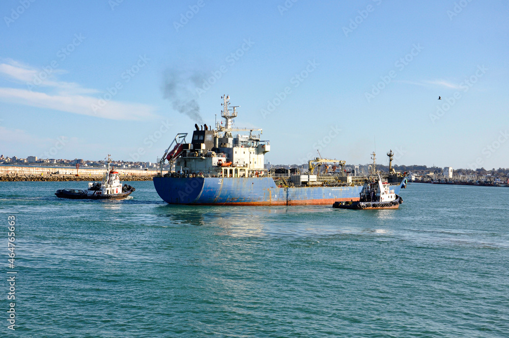 Oil tanker with tugboats at its sides entering the port of Mar del Plata