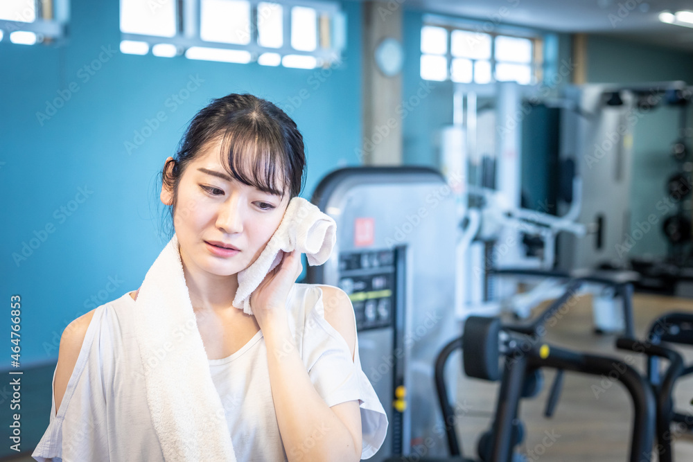 スポーツジムにいる女性(疲労・悩む)
スポーツジムにいる女性(疲労・悩む)