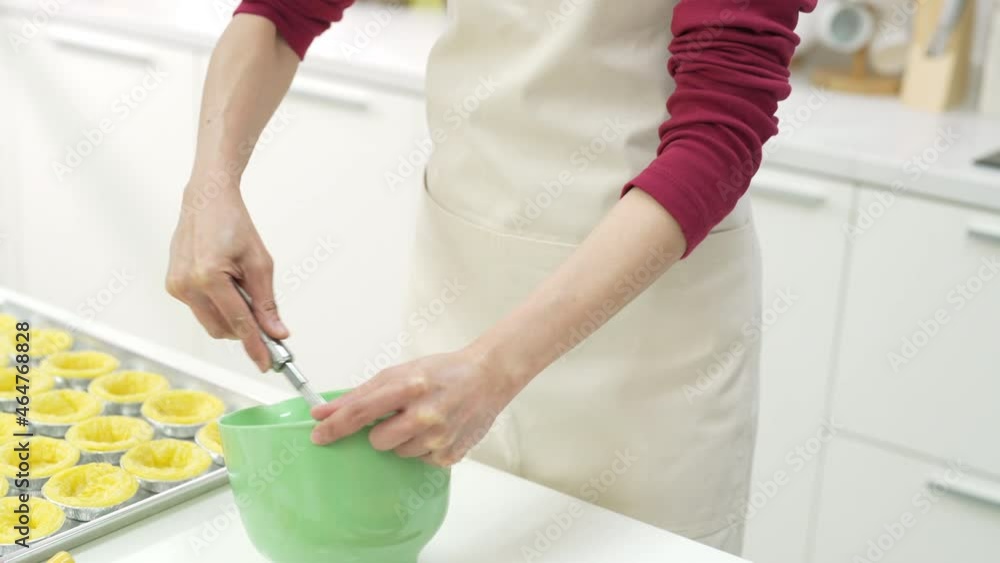 Asian woman bakery shop owner preparing bakery in the kitchen. Adult female making whipping cream from fresh milk on the table. Small business entrepreneur and indoor activity lifestyle baking concept Asian woman bakery shop owner preparing bakery in the kitchen. Adult female making whipping cream from fresh milk on the table. Small business entrepreneur and indoor activity lifestyle baking concept