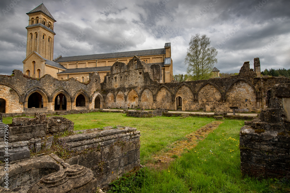 Ruines de l'Abbaye d'Orval en avant-plan du nouvel édifice sous un ciel gris menaçant