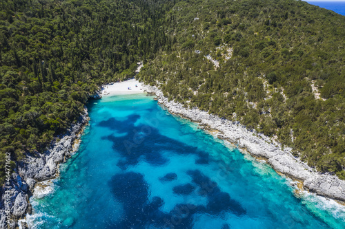 Aerial top down view of Dafnoudi beach in Kefalonia, Greece. Remote bay with pure crystal clean turquoise sea water surrounded by cypress trees