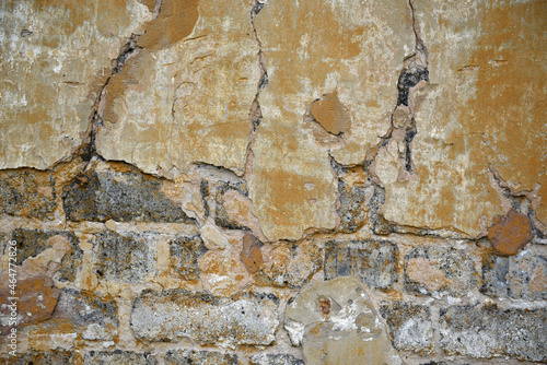 Textured background of an old wall with scuffed plaster and bricks and cracks