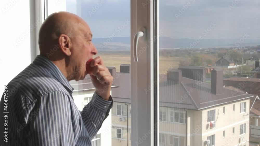 a man eating an apple and looking out the window a man eating an apple and looking out the window
