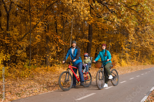 family with child riding on bikes together in autumn park