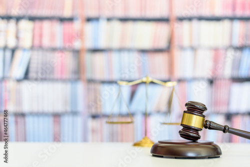 Legal office of lawyers, justice and law concept : Judge gavel or a hammer and a base used by a judge person on a desk in a courtroom with blurred weight scale of justice, bookshelf background behind photo