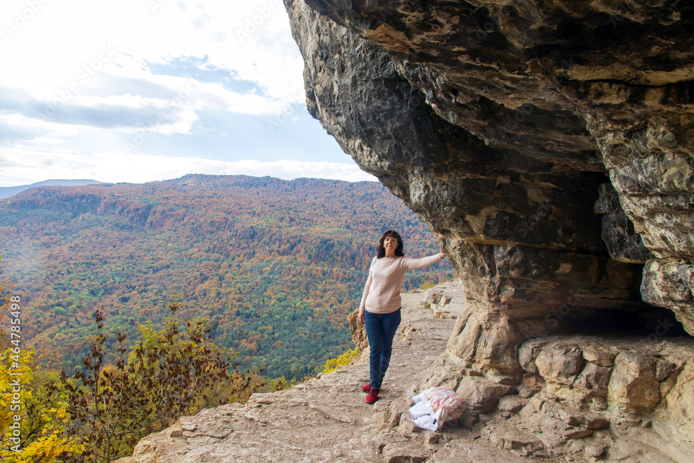 A woman is hiking on a beautiful autumn day in the mountains, relaxing on a cliff and admiring the beautiful views of the mountain peaks. Family activities, outdoor activities and healthy activities