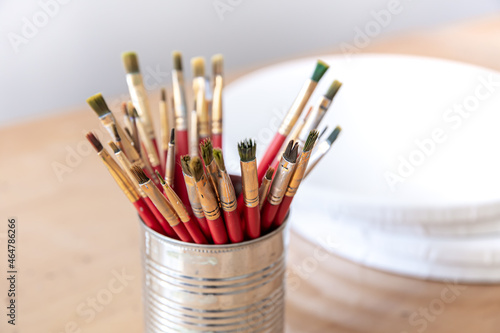 Close-up of red paint brushes in a metal jar.