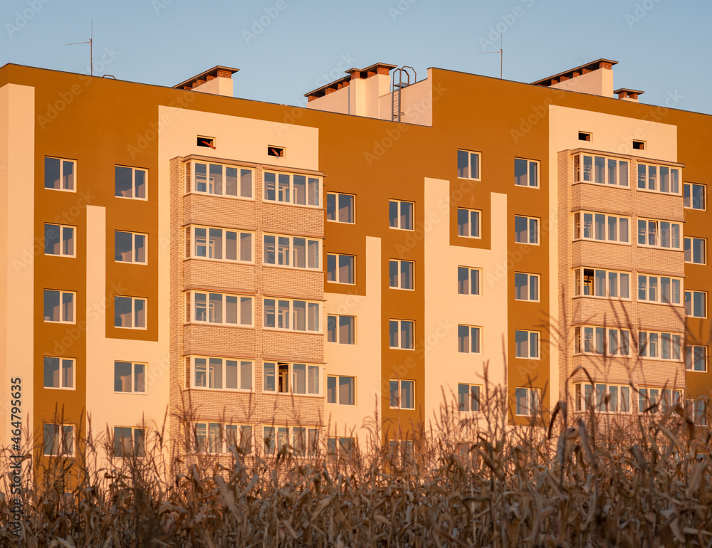 New freshly built european type Condominium apartment building without owners yet waiting for new inhabitants at sunny evening with corn in foreground