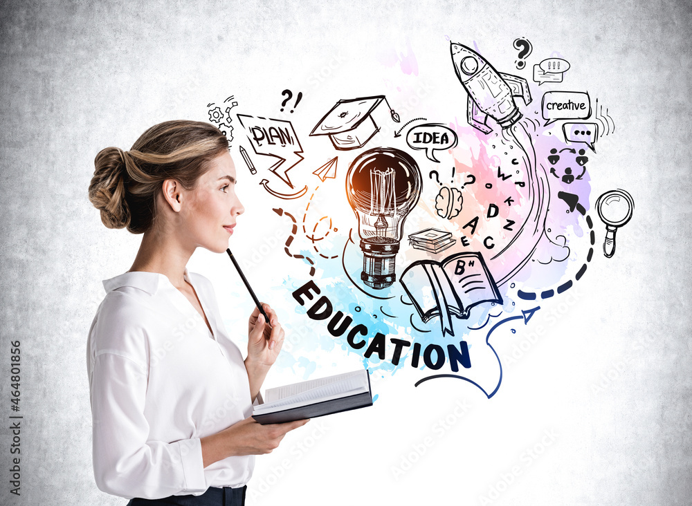 Side view of young attractive woman in white shirt is holding a notebook and pen on chin and pondering about education to start new business. Concrete wall in the background with educational sketches Side view of young attractive woman in white shirt is holding a notebook and pen on chin and pondering about education to start new business. Concrete wall in the background with educational sketches