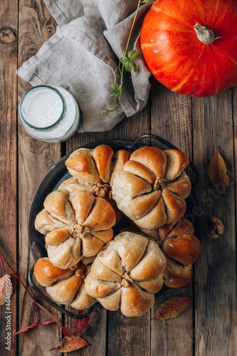 Pumpkin buns bread with cinnamon on retro tray over rustic wooden background. Autumn, Halloween food concept.