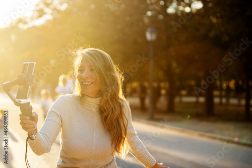 Φωτογραφία caucasian woman filming herself outdoors with a cell phone and stabilizer in the