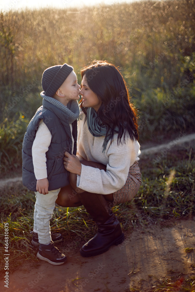 mother and her son are standing in a field with dry grass at sunset mother and her son are standing in a field with dry grass at sunset