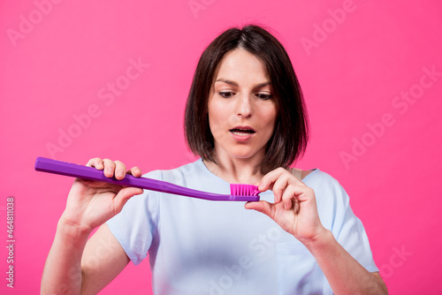 Beautiful happy young woman with big toothbrush on blank pink background