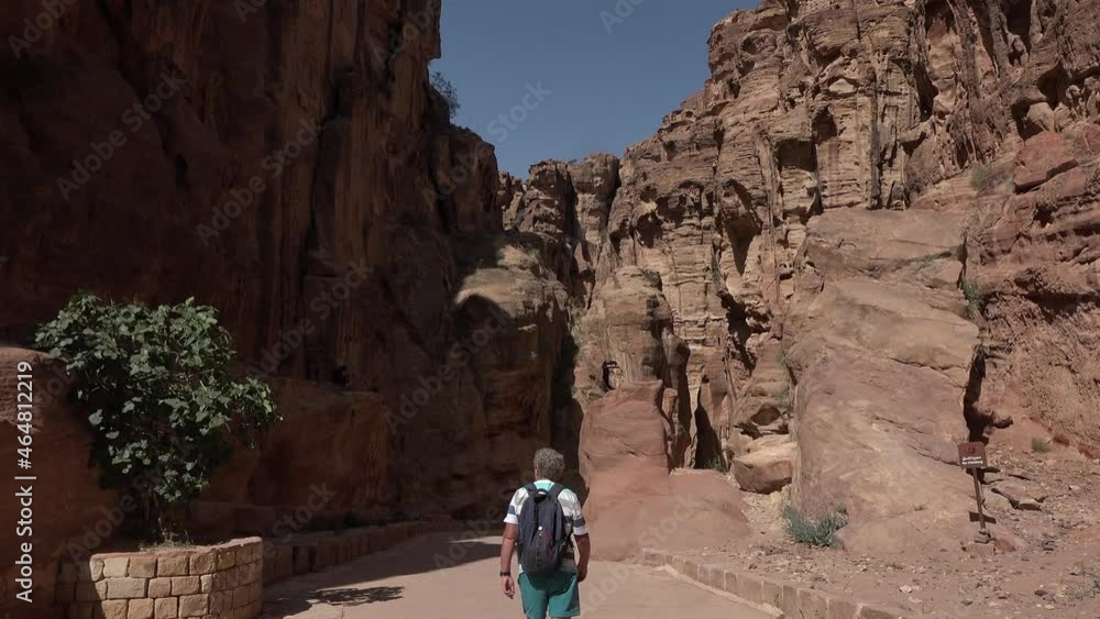 Petra, Jordan May 7 2021: Tourist walking through ruins of Petra, with ancient Nabatean buildings carved in rocks of the the valley. Petra, Jordan May 7 2021: Tourist walking through ruins of Petra, with ancient Nabatean buildings carved in rocks of the the valley.