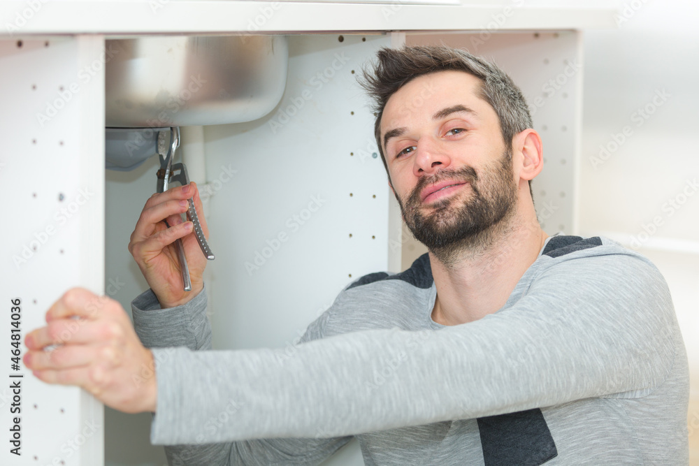 male plumber installing kitchen sink using wrench male plumber installing kitchen sink using wrench