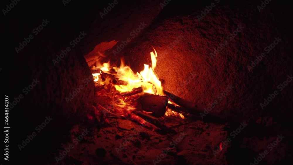 Dry wood burns with bright orange flame in bonfire spreading little sparks near rocks on wild beach at late night Vietnam closeup Dry wood burns with bright orange flame in bonfire spreading little sparks near rocks on wild beach at late night Vietnam closeup