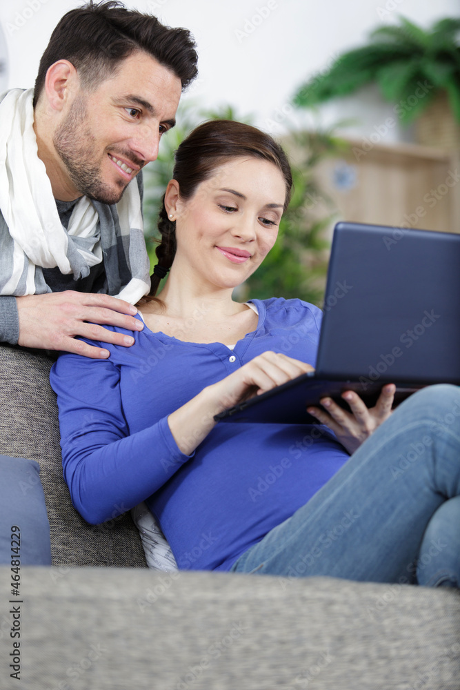 couple with pregnant woman using laptop computer