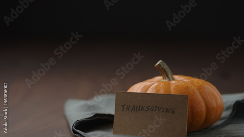 thanksgving card next to orange pumpkin on walnut table photo