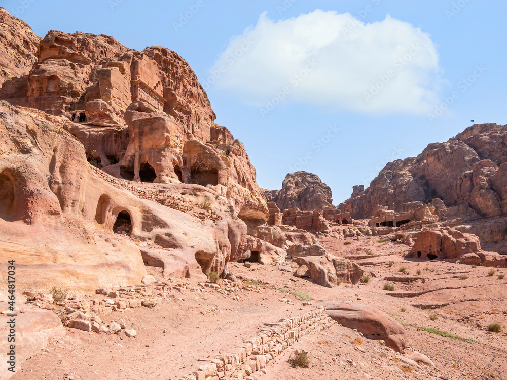 Ancient housing carved in red sand rock in the city of Petra, Jordan.