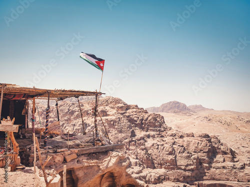 Jordanian flag waving in the wind at a viewpoint in the ancient city of Petra, Jordan.