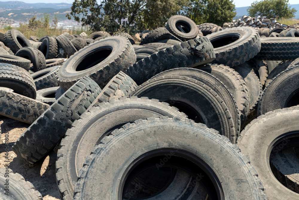 A lot of different old, dirty worn out car tires in a garbage. One of the factors affecting environmental pollution.