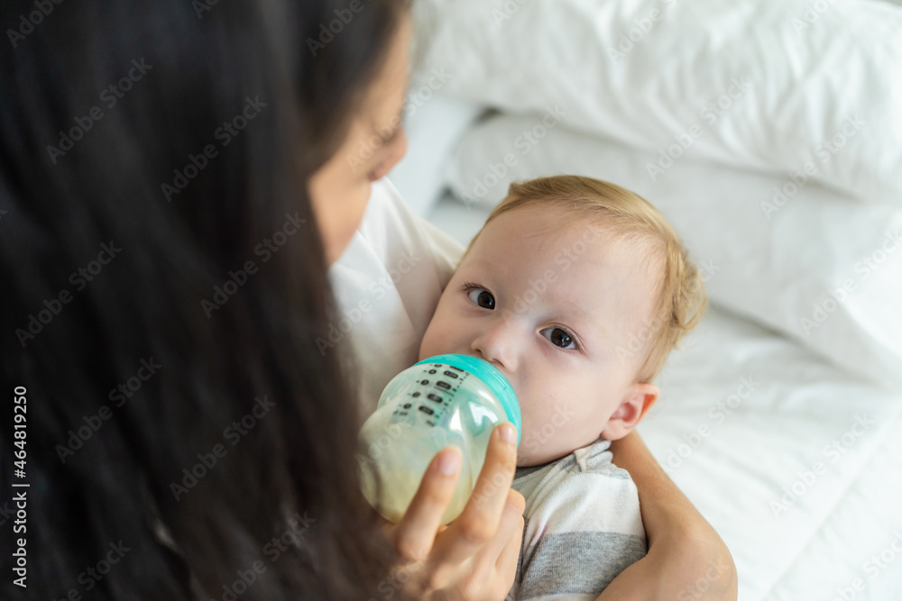 Caucasian beautiful mother holding and feeding baby from milk bottle. Caucasian beautiful mother holding and feeding baby from milk bottle.