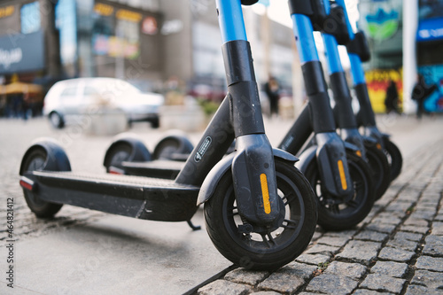 Row of electric scooters parked in the city. Modern battery-powered rental vehicles for the transport of people - Concept new trends of sustainable urban mobility. 