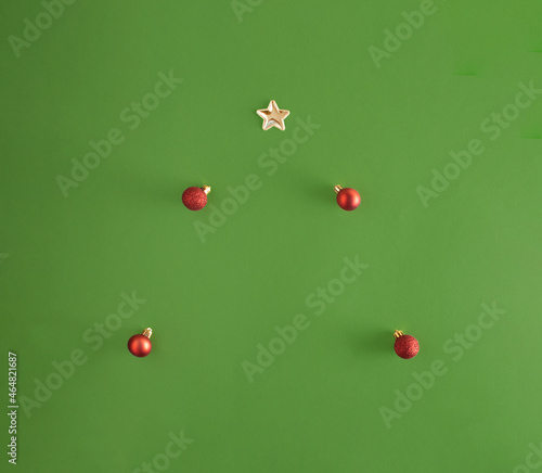 Minimal creative Christmas composition. Red glossy and matte red baubles and golden star forming an imaginary fir tree. 