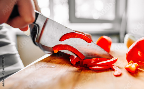 Chefs woman hands chopping red pepper on wooden board