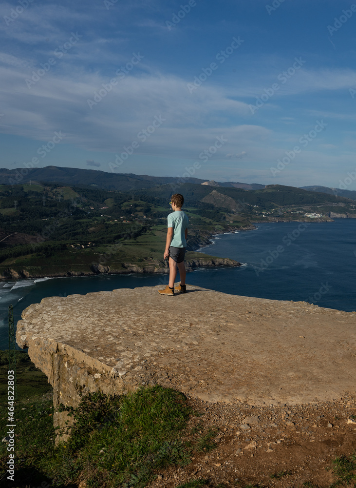 boy on a rock high above watching the sea