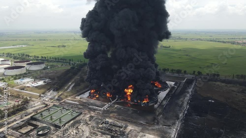 Aerial footage of a large scale Oil refinery with smoke because explosions stacks and petroleum storage tanks