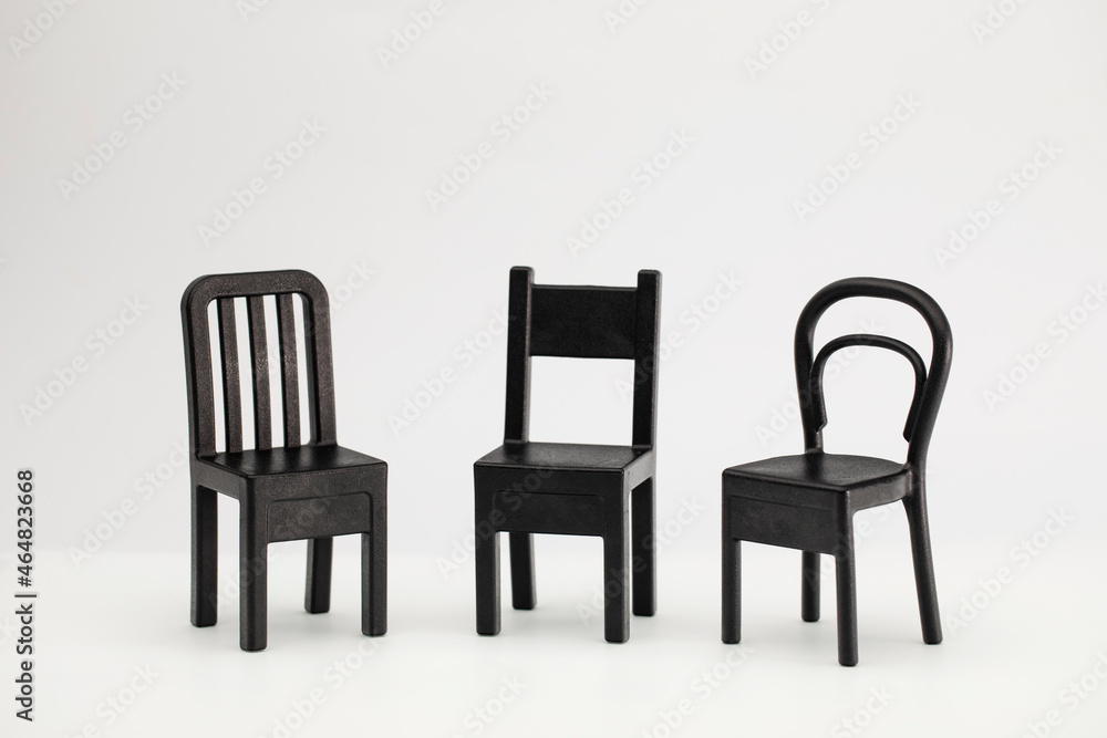 Fototapeta premium Three black chairs on a white background