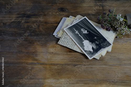 stack of retro monochrome photographs of 50-60s on natural wooden table, photo of child, dried flowers, concept of family tree, genealogy, connection with ancestors, memories of youth, childhood
