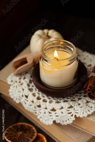 Autumn composition with aromatic candle, cinnamon, pumpkin. Old books, knitted vintage napkin as decor