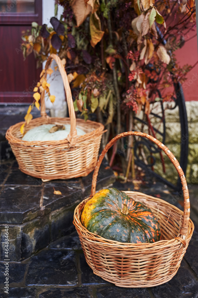 two large pumpkins in wicker baskets on the porch