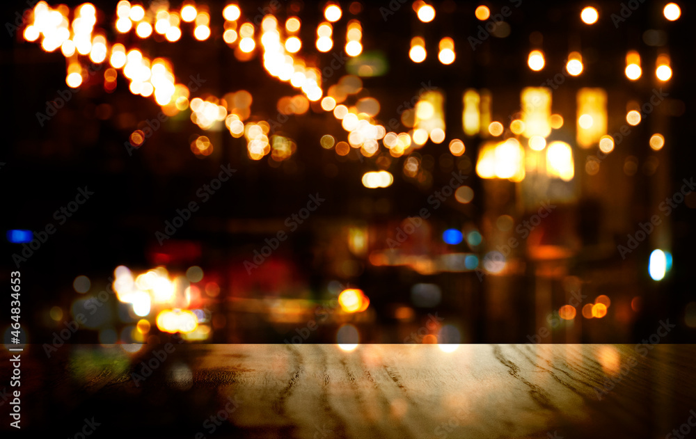 op of black wood table with blur light of party for Christmas of bar or pub in dark city night abstract background