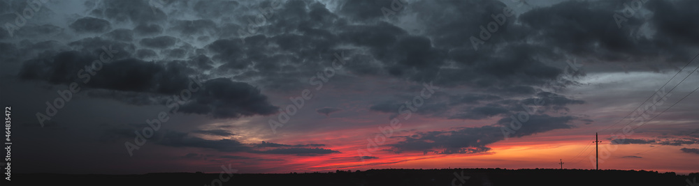 sunset panorama with raspberry clouds over a small town against a blue sky sunset panorama with raspberry clouds over a small town against a blue sky