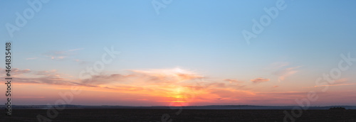 sunset panorama with raspberry clouds on a blue sky background