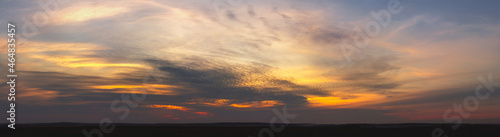 Sunset in orange tones with fluffy clouds and trees.