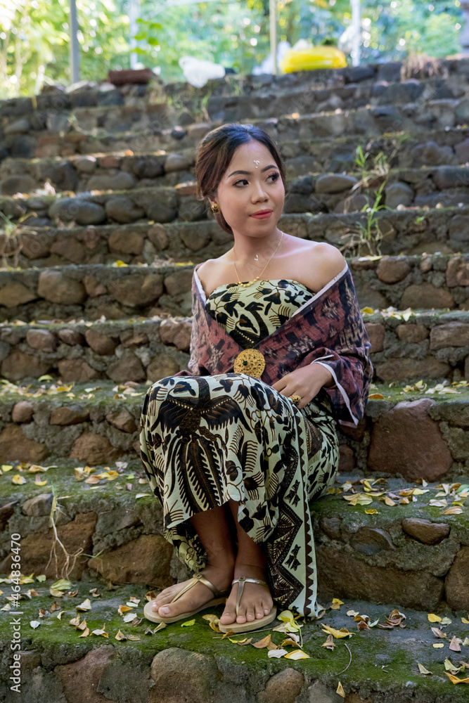 Balinese girl posing in nature and in a forest on Candidasa's offshore islands in Bali, dressed in a traditional costume. 