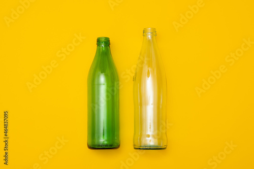 Two empty glass bottle on a yellow background. Eco-friendly packaging, waste recycling concept, glass waste, rubish sort and plastic free lifestyle. photo